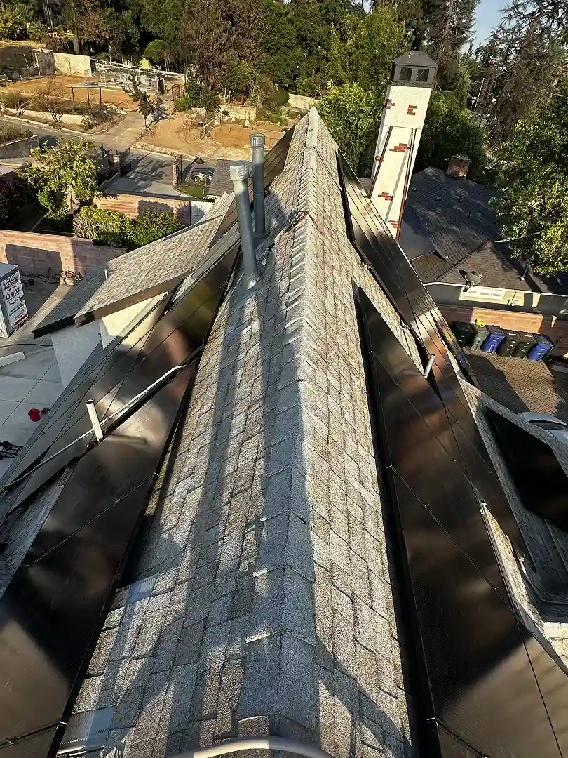 Solar panels installed across multiple roof faces of Altadena home, view along the ridge