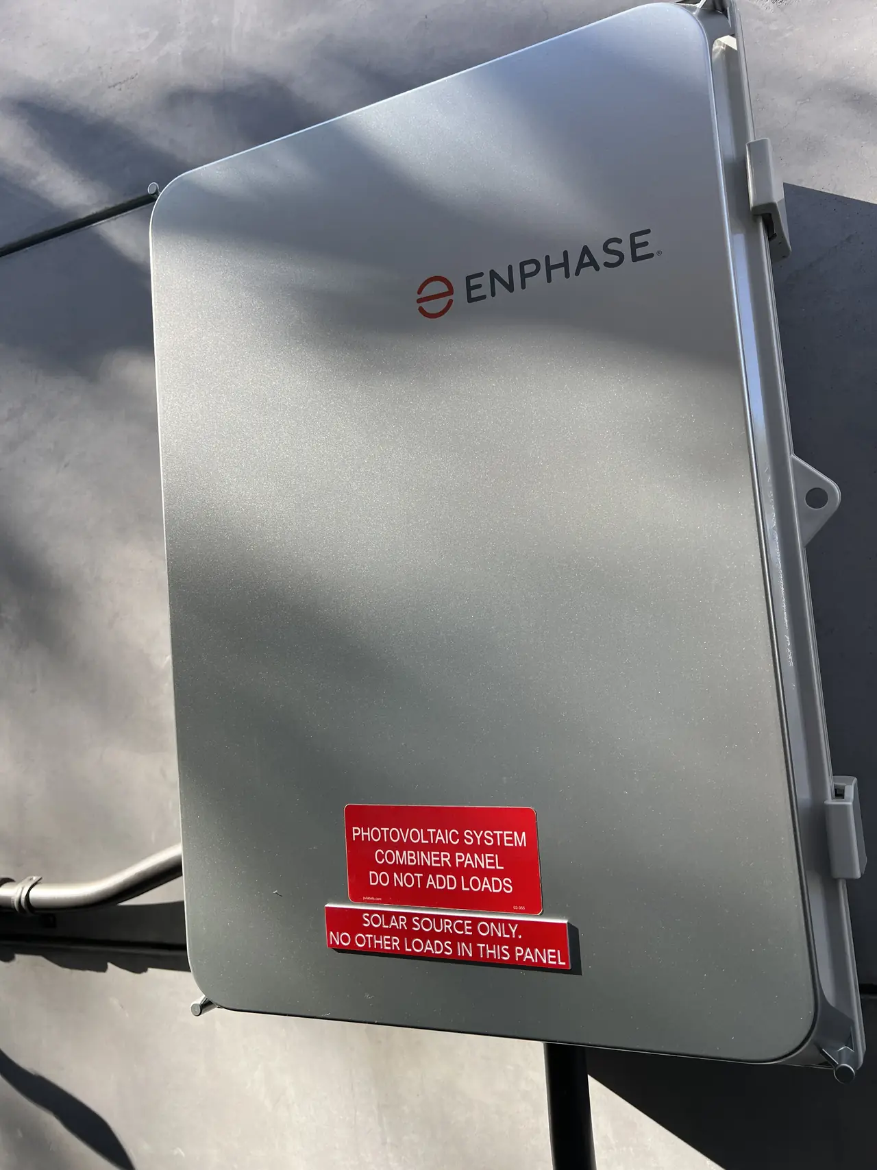 Enphase combiner panel on the exterior wall of a Burbank house, with photovoltaic system labels