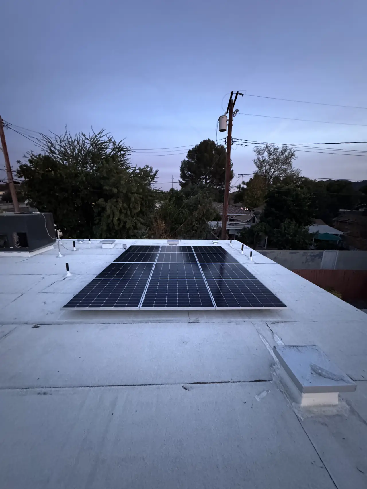Six-module solar array on a white flat roof in Burbank with a conduit run along the roof surface