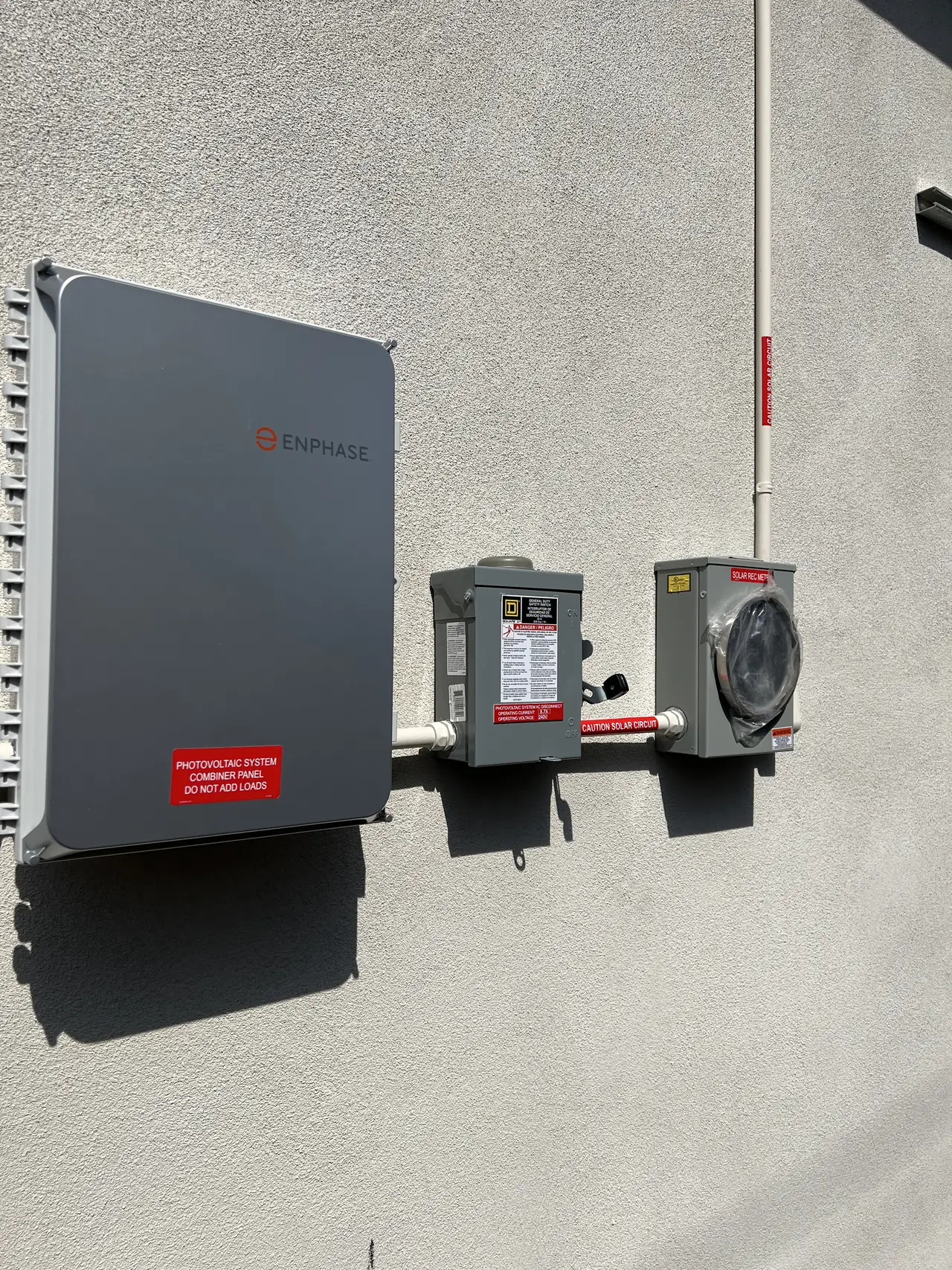 Combiner panel, alternating current disconnect and utility solar meter socket on a stucco wall in Burbank