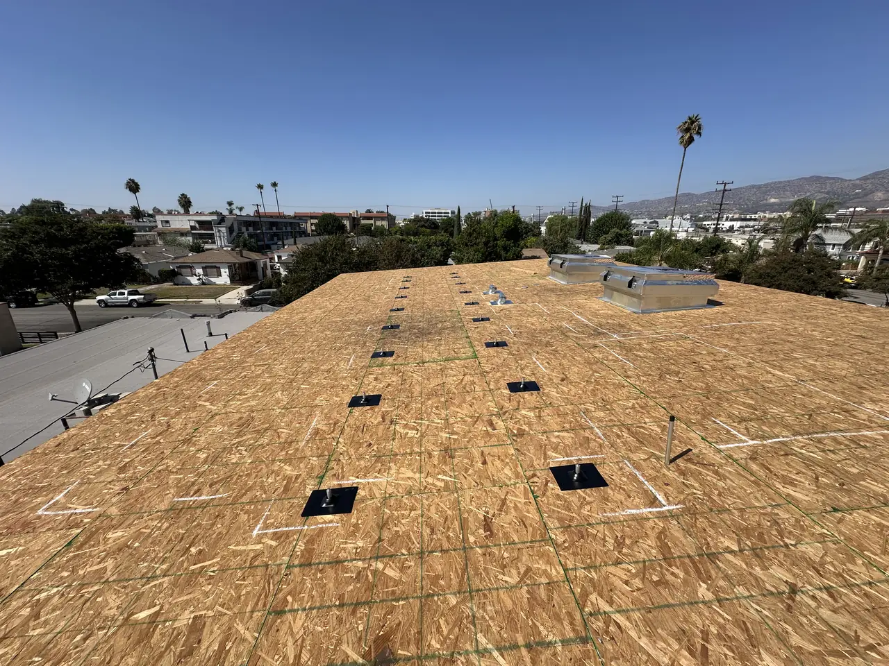Bare roof sheathing on a Burbank house under construction with mounting positions marked