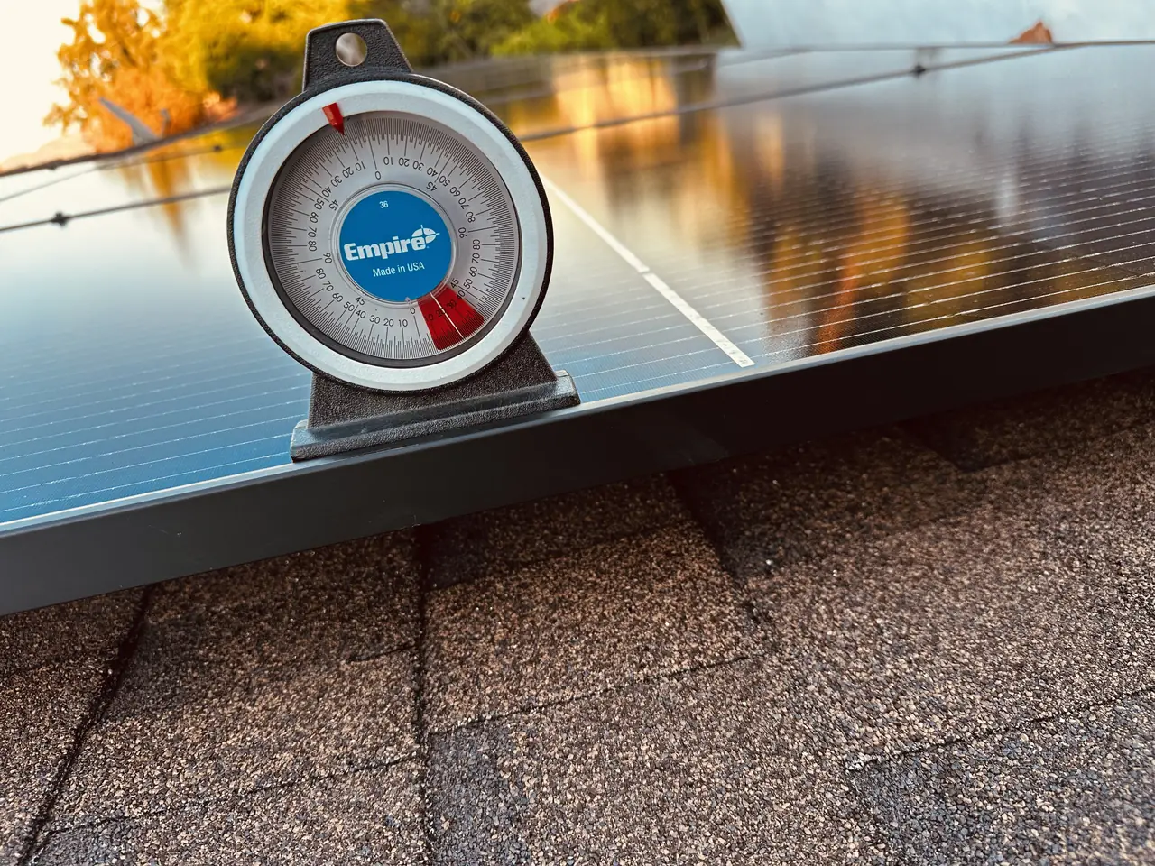 Angle finder resting on the edge of a solar module on a Burbank roof to read the pitch