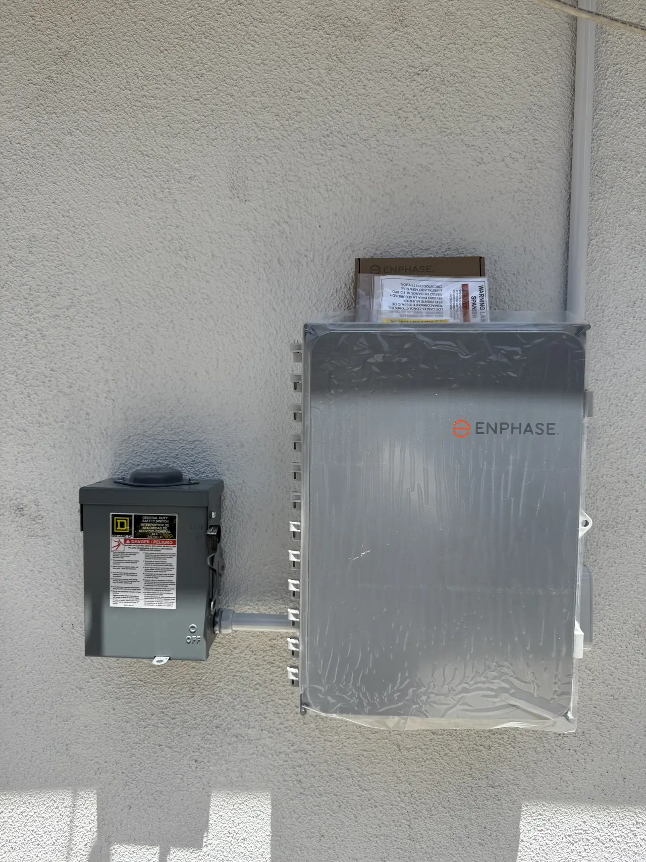 Combiner panel and an electrical enclosure on a stucco wall in Burbank, beside conduit