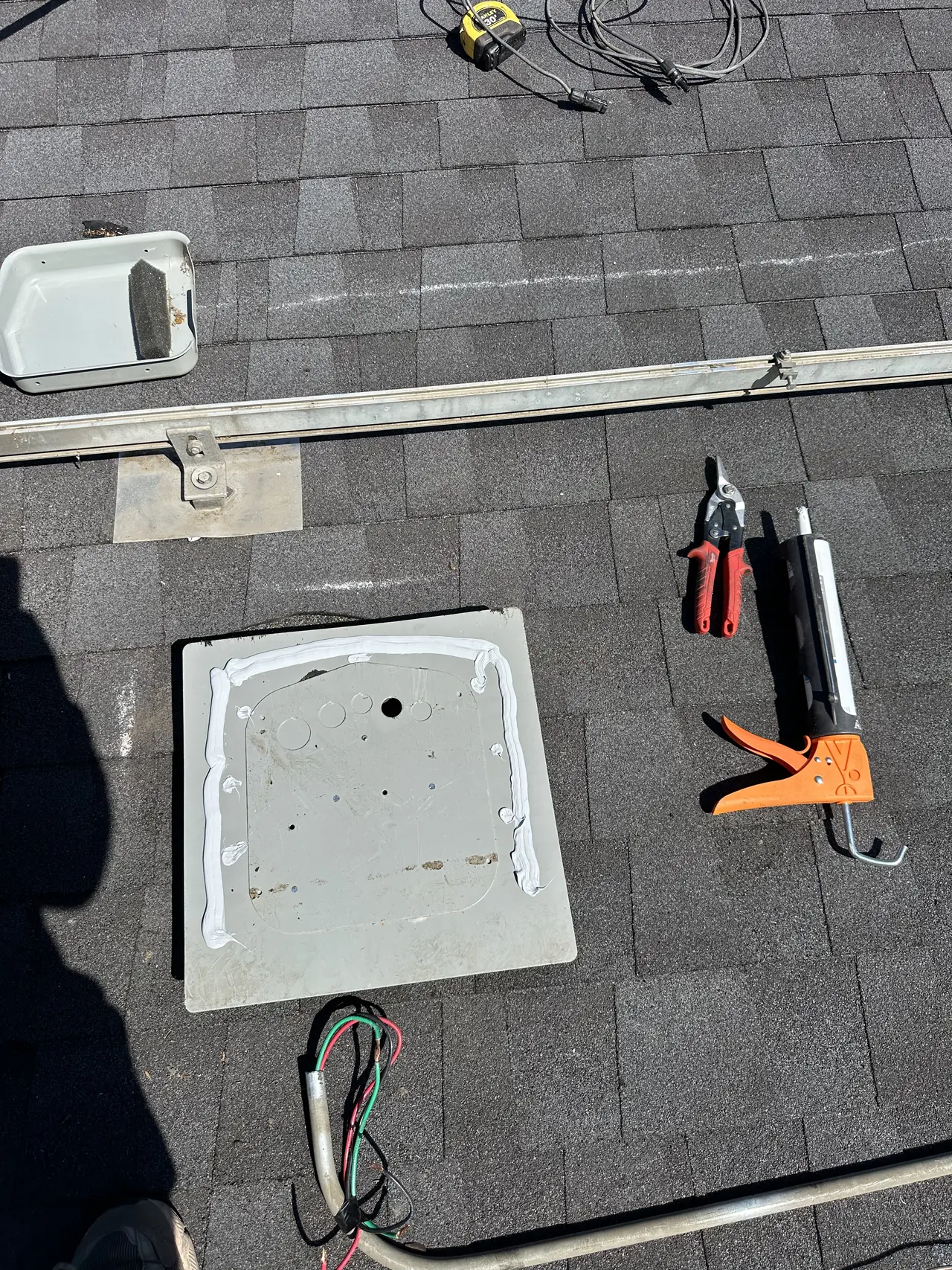 New mounting plate bedded on sealant on a fresh shingle roof in Burbank, with rail and a mounting foot alongside