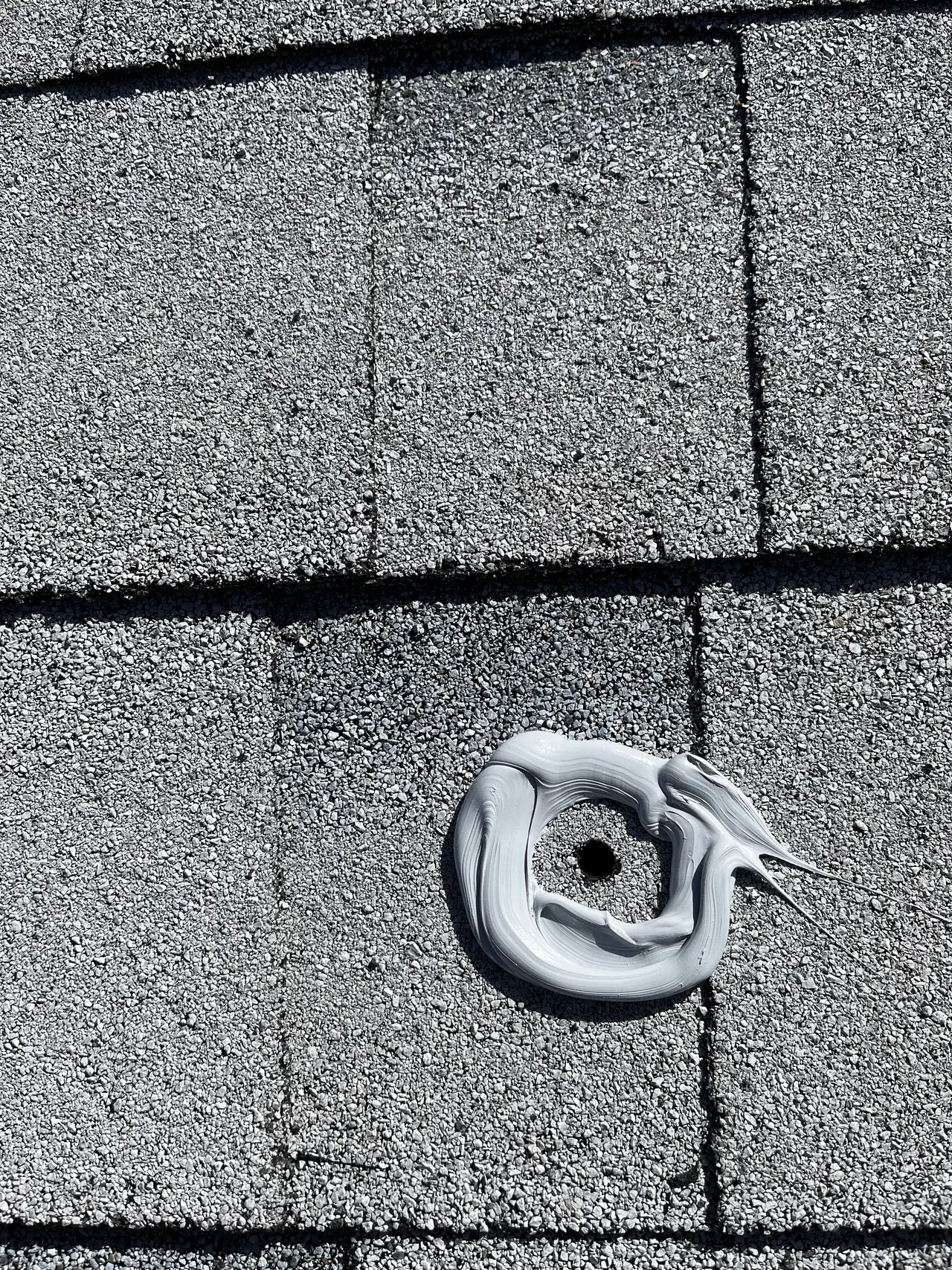 A ring of sealant laid around a drilled mount hole on a new white shingle roof, Calabasas