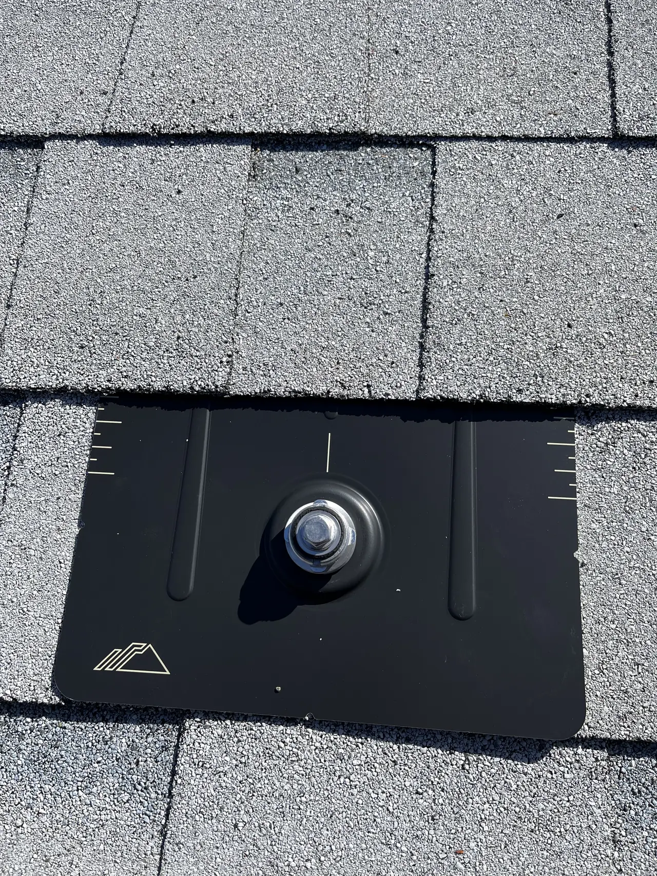 A black flashed solar mount with its bolt set on a new white shingle roof, Calabasas