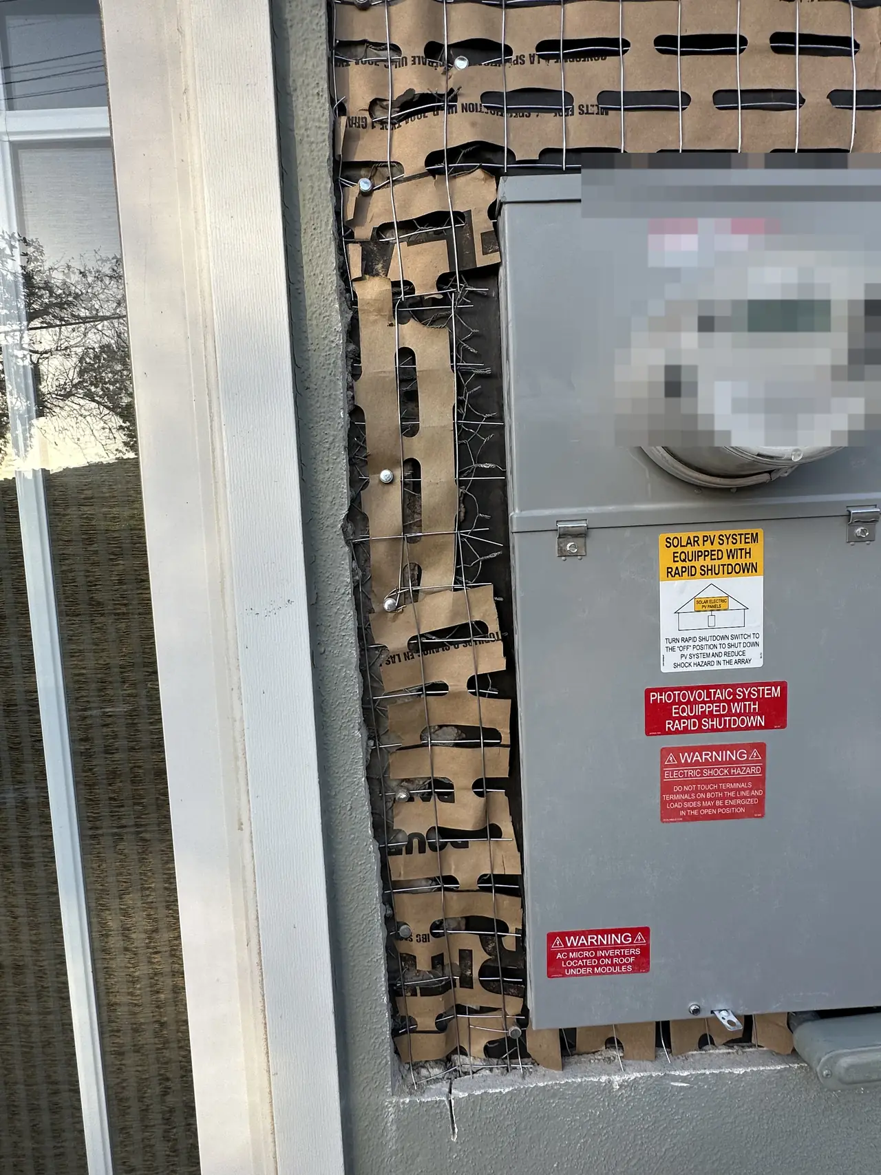 A new meter and service panel with solar placards set into an opening in a stucco wall, Calabasas