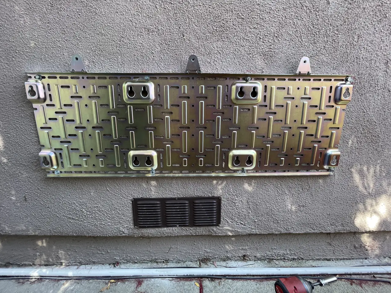 Steel mounting frame bolted to a stucco wall before the battery units are hung on it, Encino