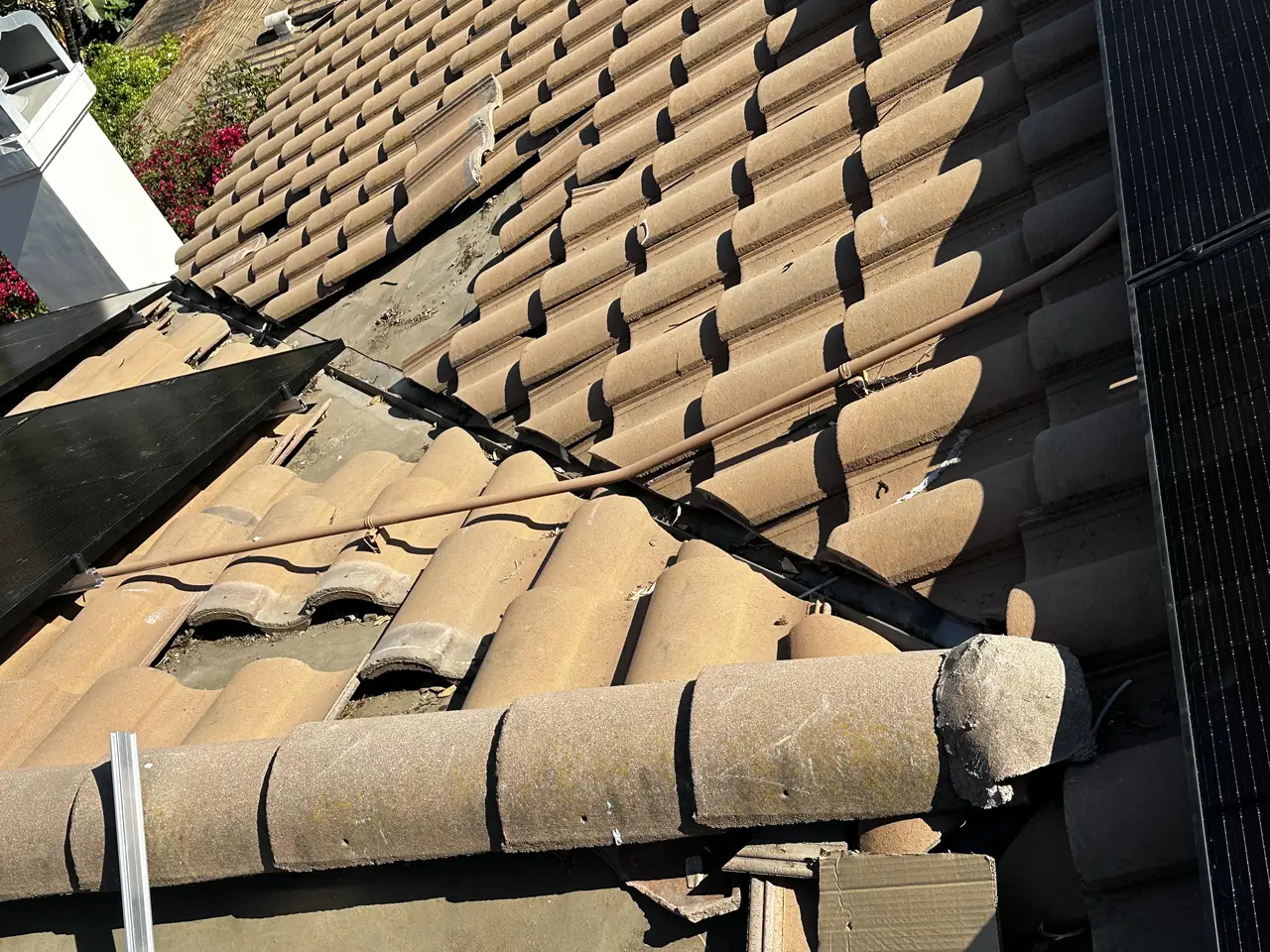 Concrete roof tiles lifted out at the mount points on a tile roof, exposing the batten and deck beneath, Encino