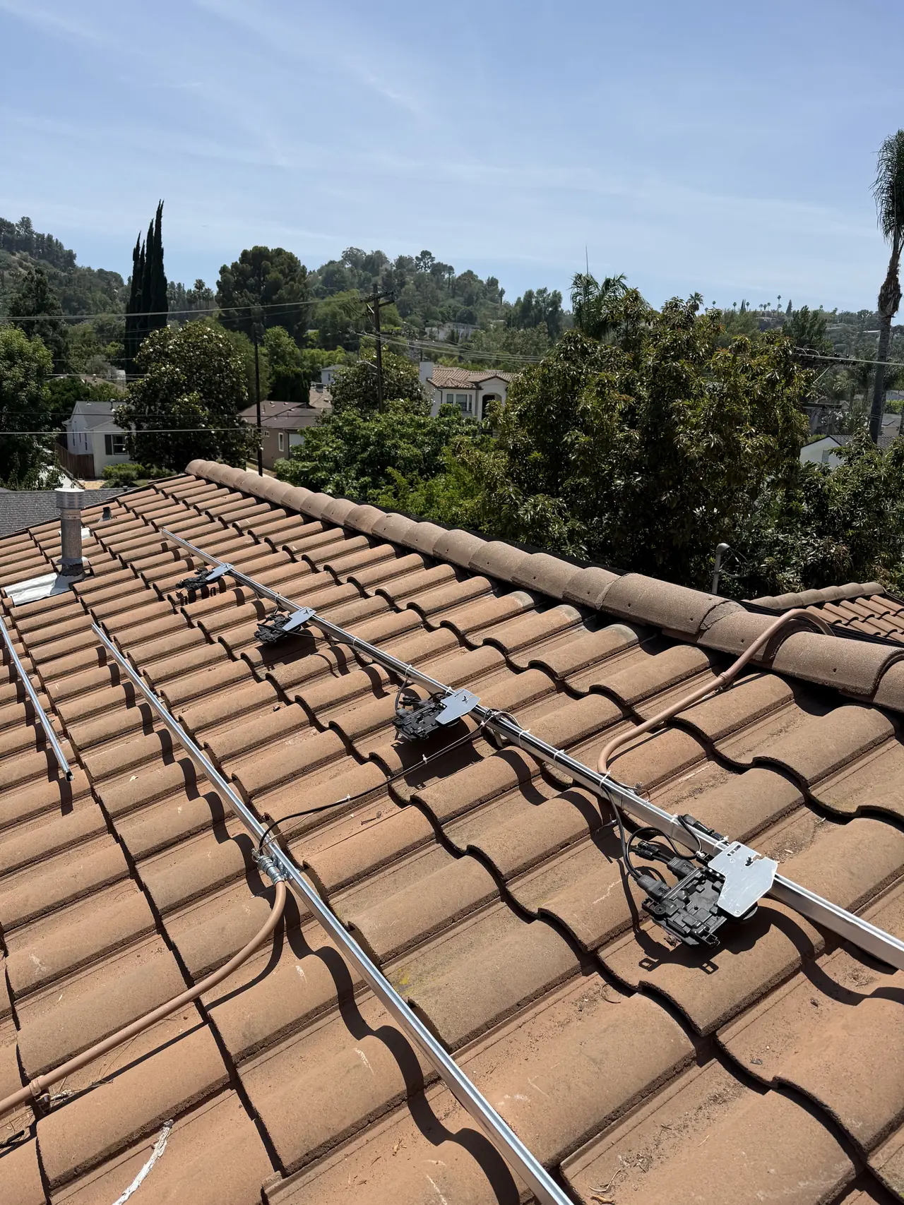 Aluminum rails and Enphase microinverters mounted across a concrete tile roof before the modules go on, Encino