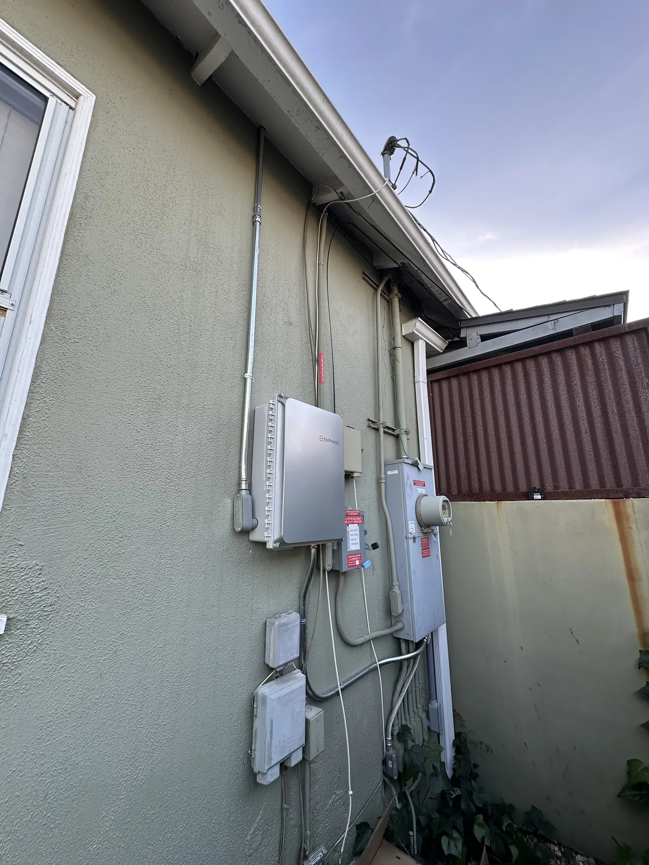 Stucco wall with two enclosures and conduit runs beside the existing service equipment, Encino