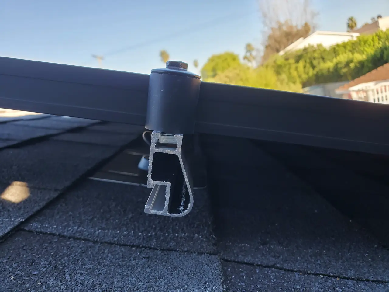 Standoff and rail end above new composition shingle, seen along the run of the rail, Encino