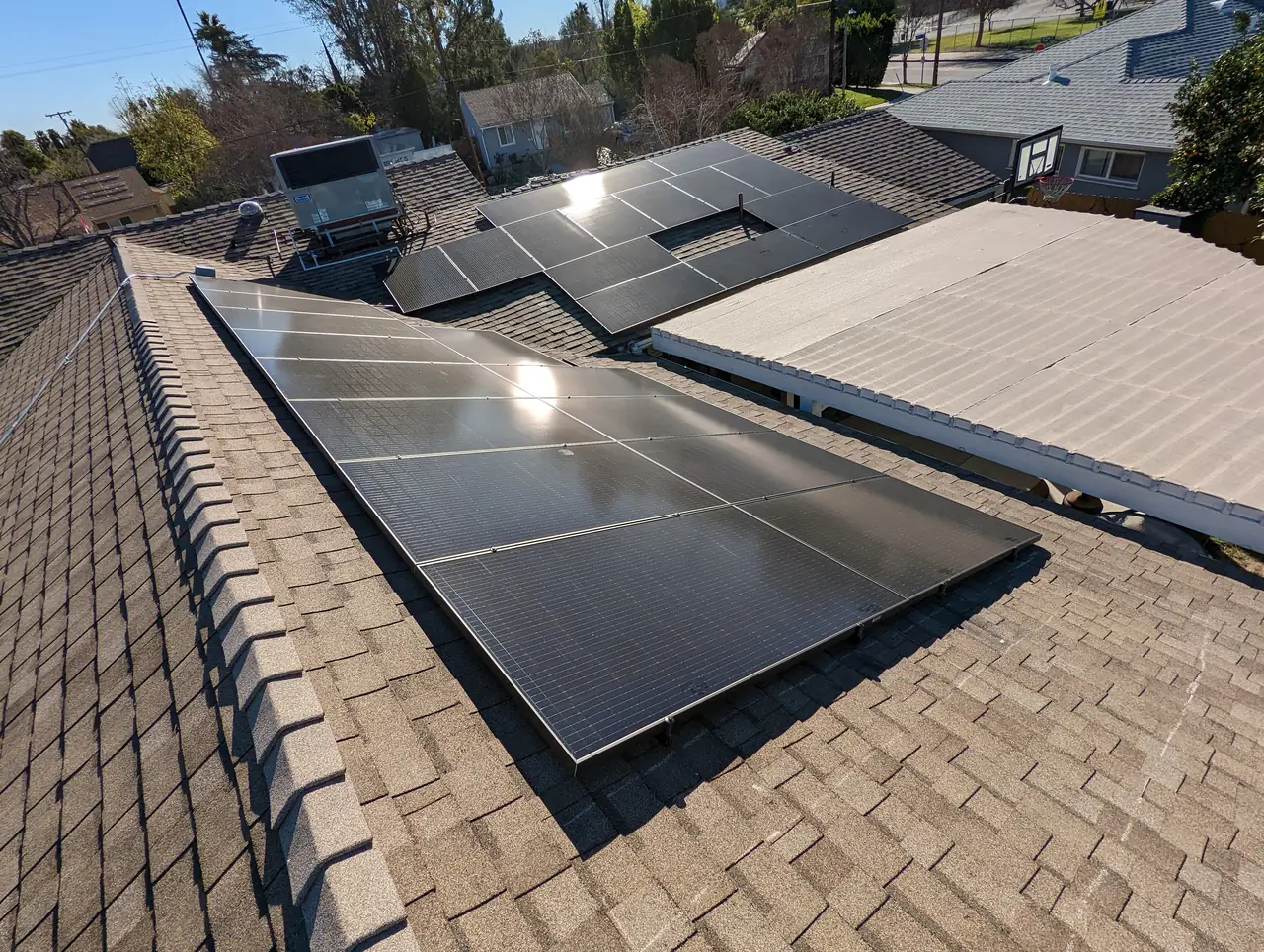 Solar modules along the ridge of a shingle roof with a rooftop air conditioning unit beyond, Encino