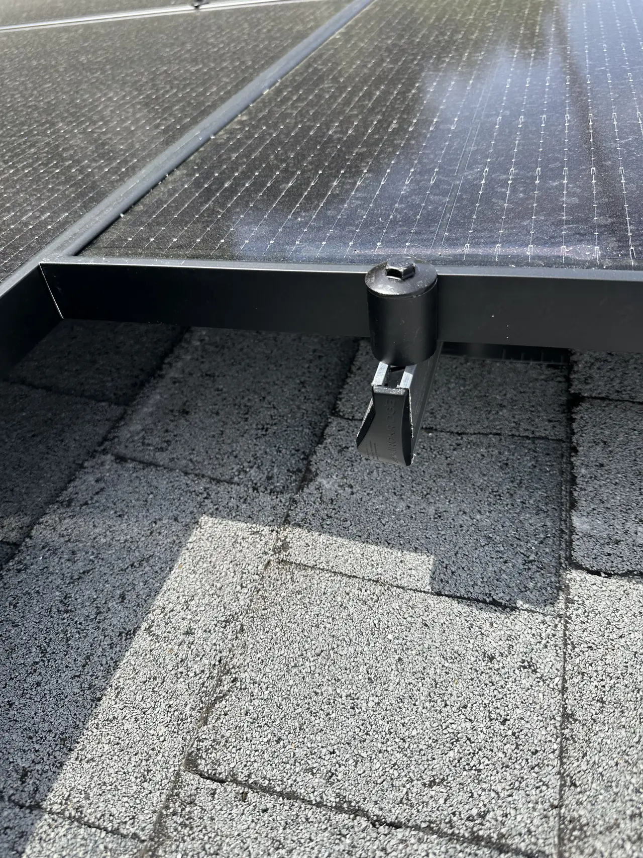 Standoff and rail on composition shingle with flashing at the base, seen from under the module edge