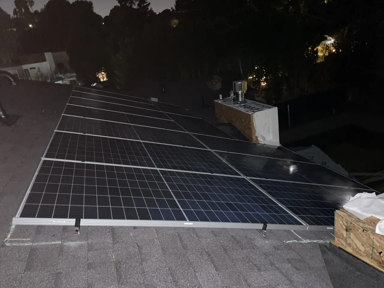 Rows of solar modules on a shingle roof at dusk, with the valley lights beyond, Encino