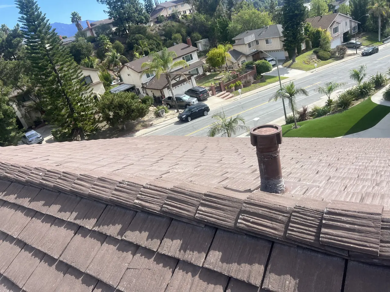 Old concrete tile roof with a chimney in the foreground and a suburban street below, Glendale