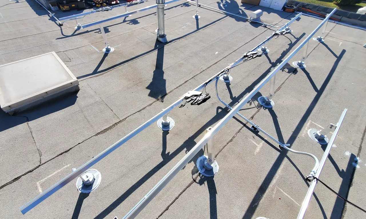 Aluminum rails on tilted stands across a flat built-up roof, with vents and a skylight, Glendale