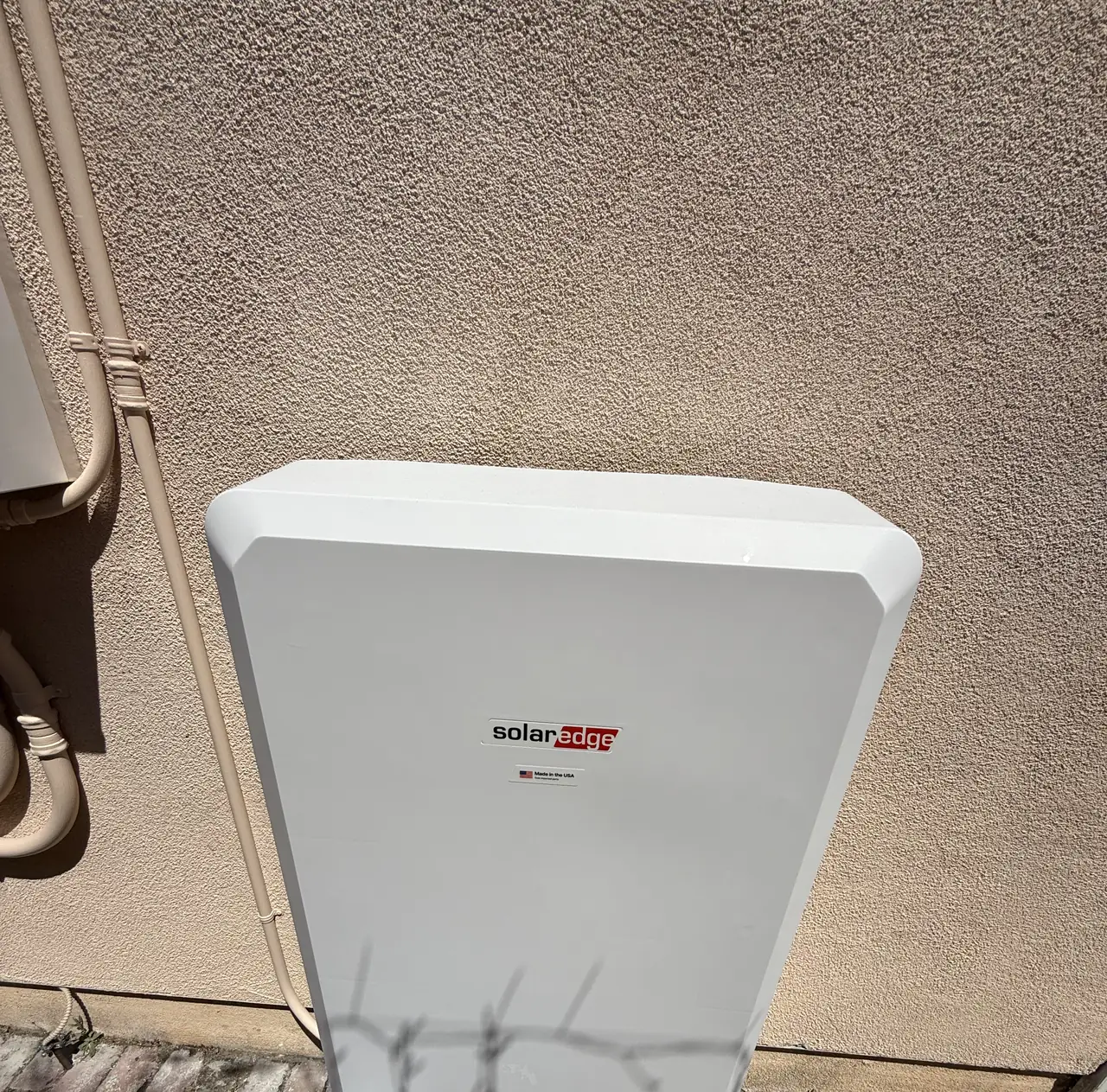 Close view of the home battery mounted flat against a stucco wall, Glendale