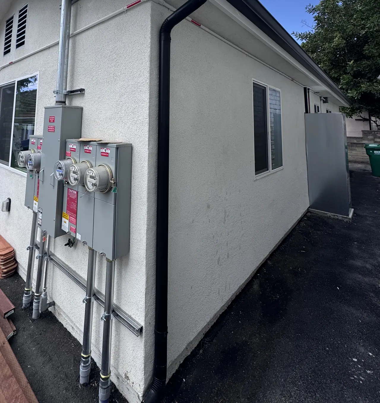 New accessory dwelling unit under a blue sky with a bank of meter sockets and disconnects on its end wall, Glendale