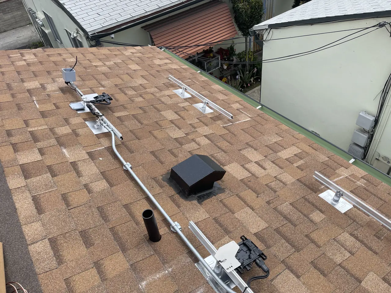 Mounting rails with a microinverter attached, on a new composition shingle roof with a vent and conduit, Glendale