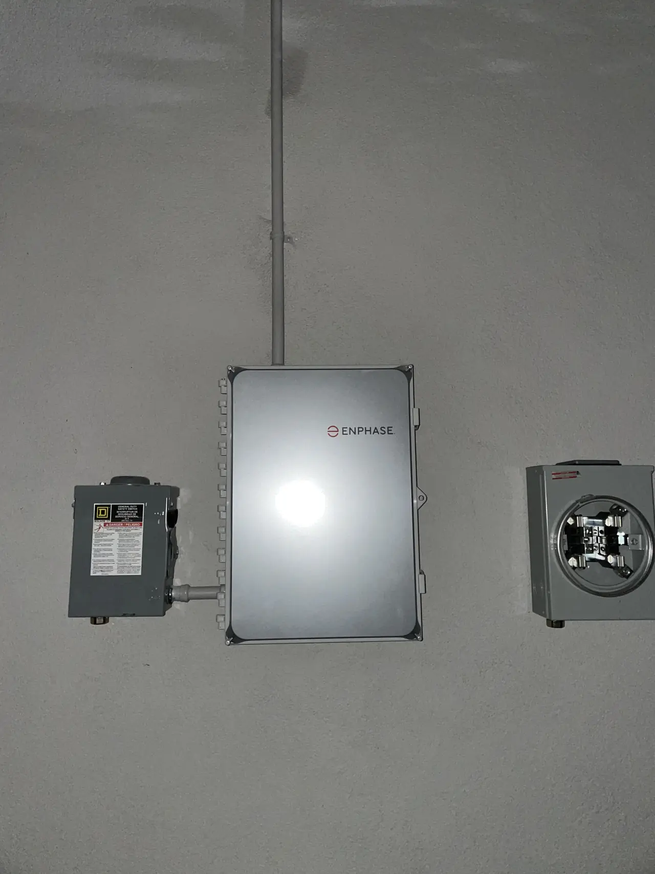 Combiner box, disconnect and new meter socket on a stucco wall at night, Glendale