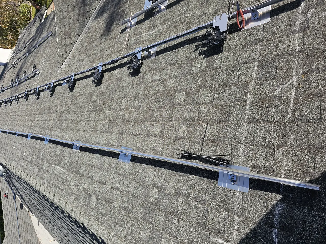 Mounting rails and flashings installed on a composition shingle roof before the modules