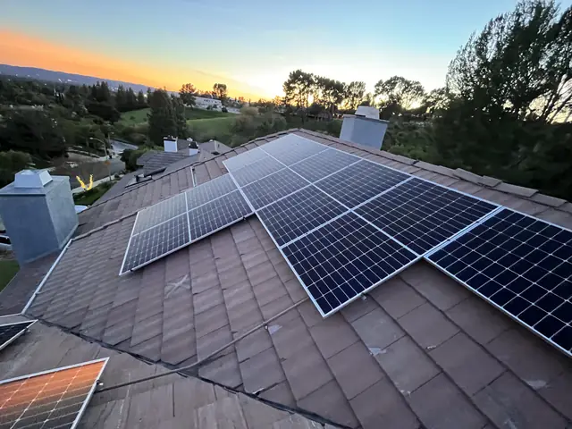 Solar modules across several planes of a concrete tile roof at sunset, with the valley beyond, Granada Hills