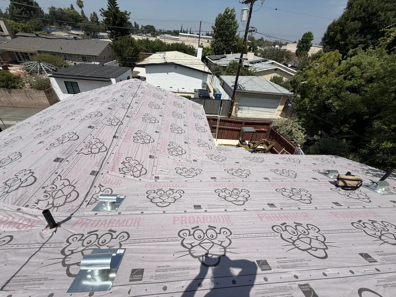 A flat roof covered in underlayment with a rooftop condenser, neighboring roofs beyond, Granada Hills