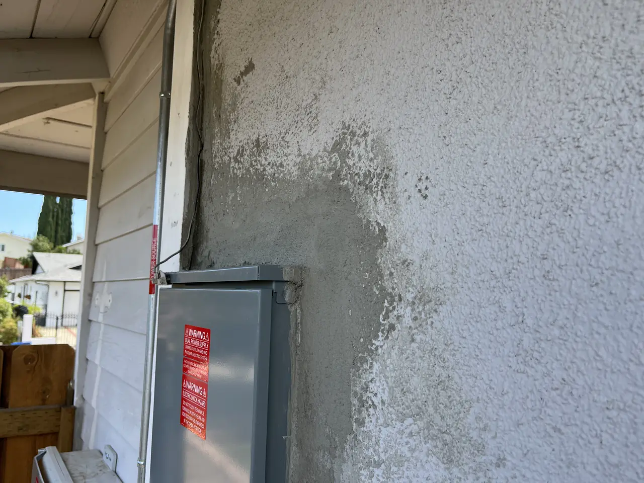 Fresh stucco patched around a newly installed service panel on an exterior wall, Granada Hills