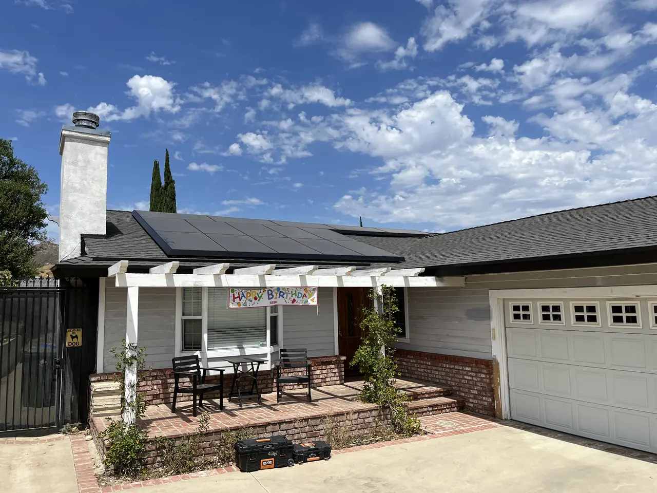 A single-story house with a dark solar array on the roof, a pergola over the front patio and a two-car garage, Granada Hills