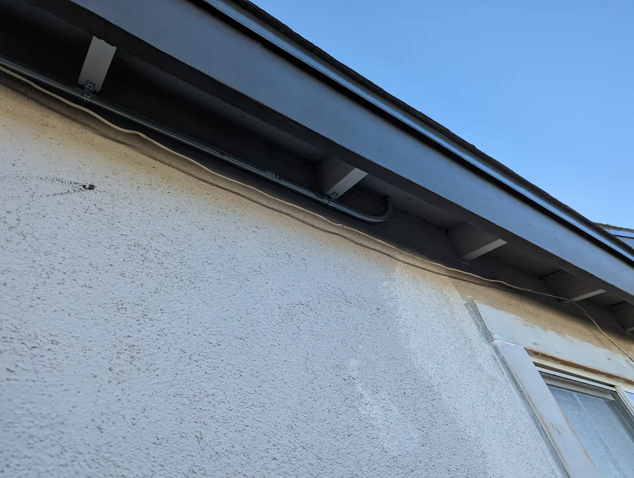 The eave and fascia line of a single-story house against a clear sky, Granada Hills