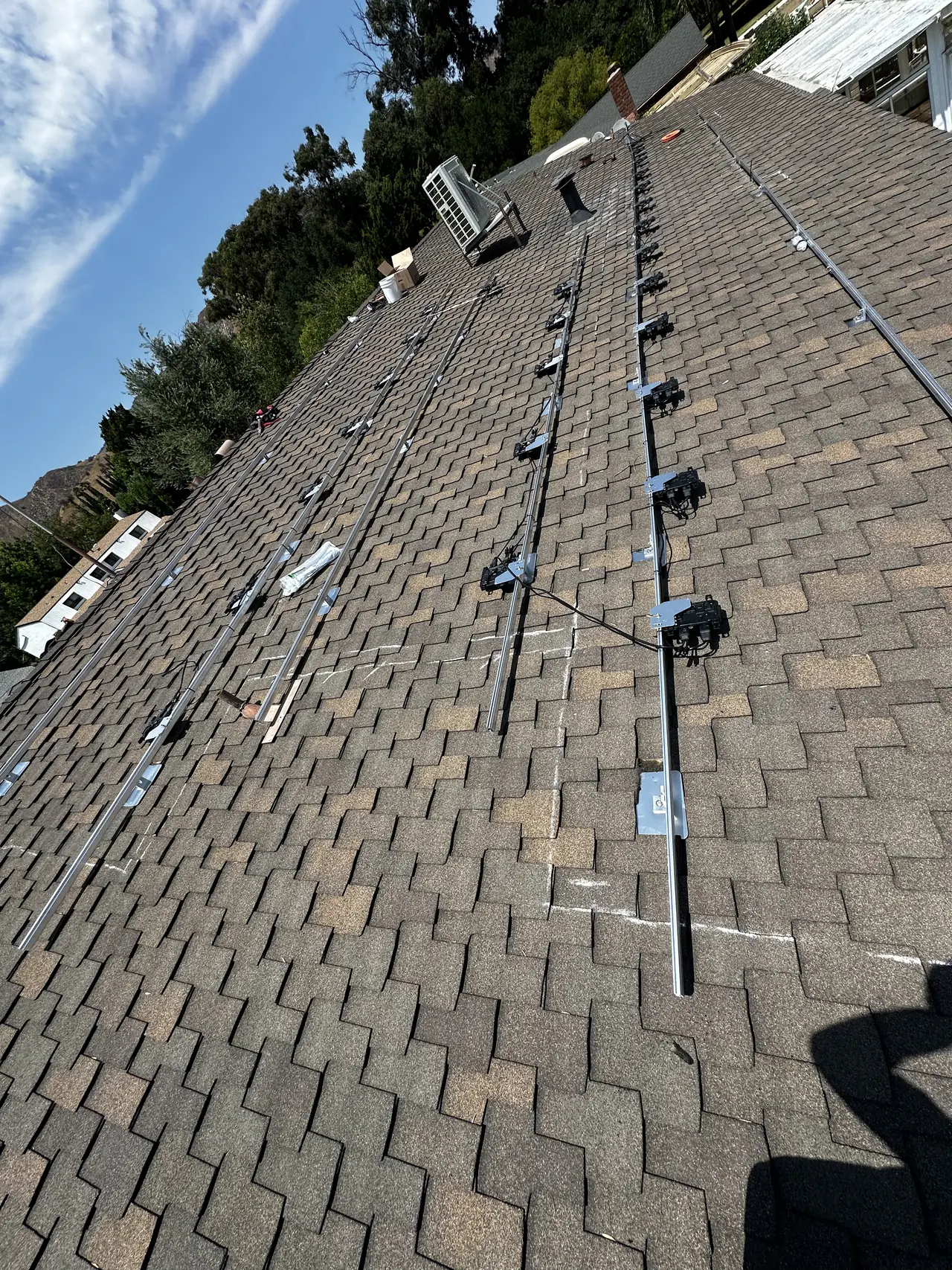 Mounting rails and attachments laid out across a shingle roof before the modules, Granada Hills
