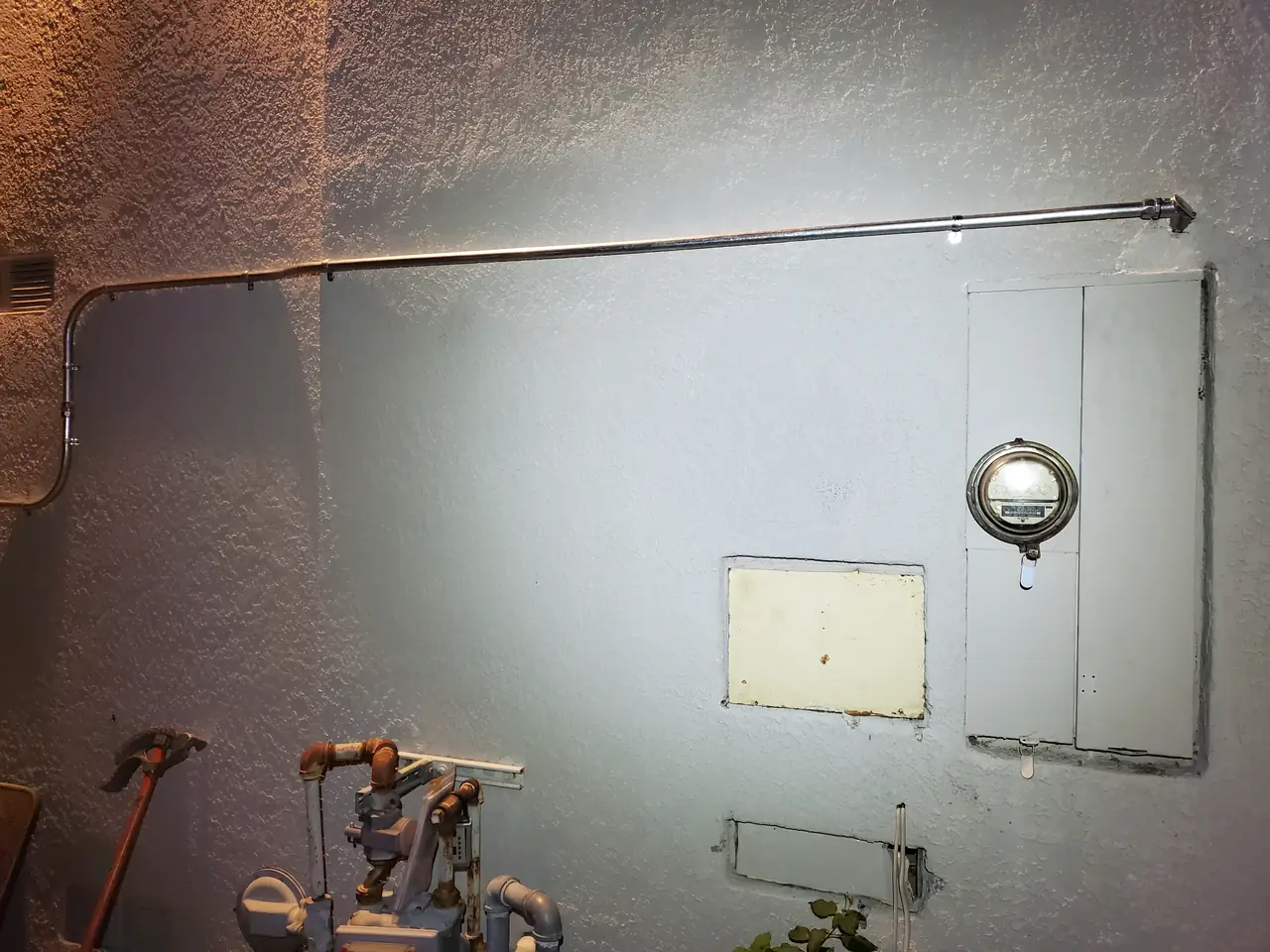 An exterior utility wall with copper pipe, a meter and two patched access panels, Granada Hills