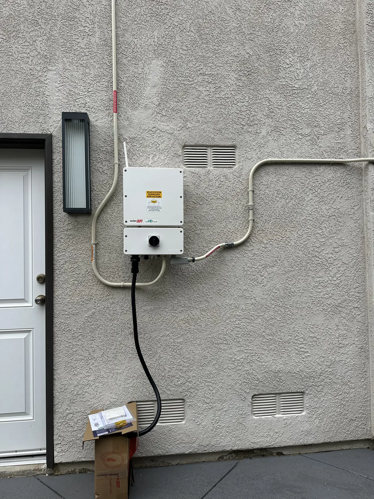 A string inverter mounted on a stucco wall beside an exterior door, Granada Hills