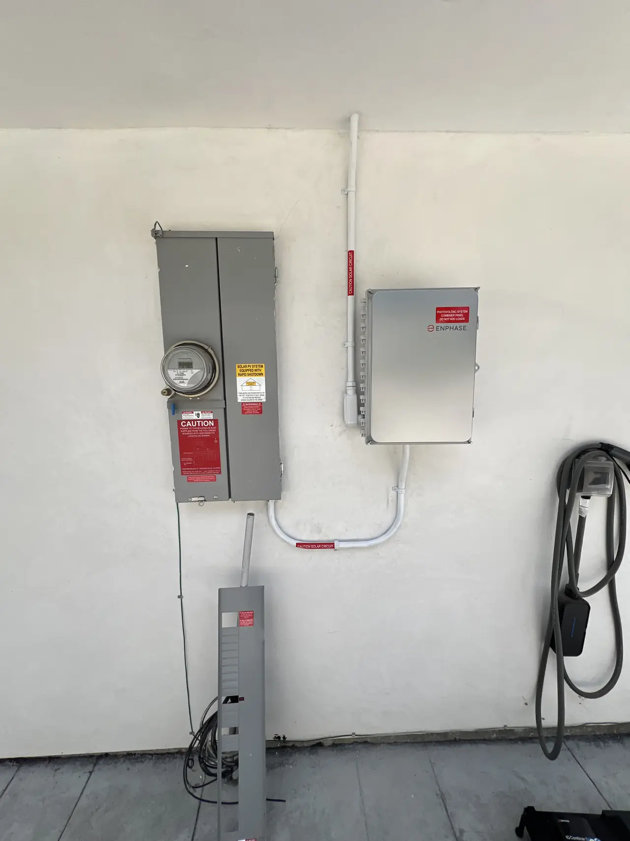 A meter, service panel and combiner enclosure mounted on a white exterior wall, Granada Hills