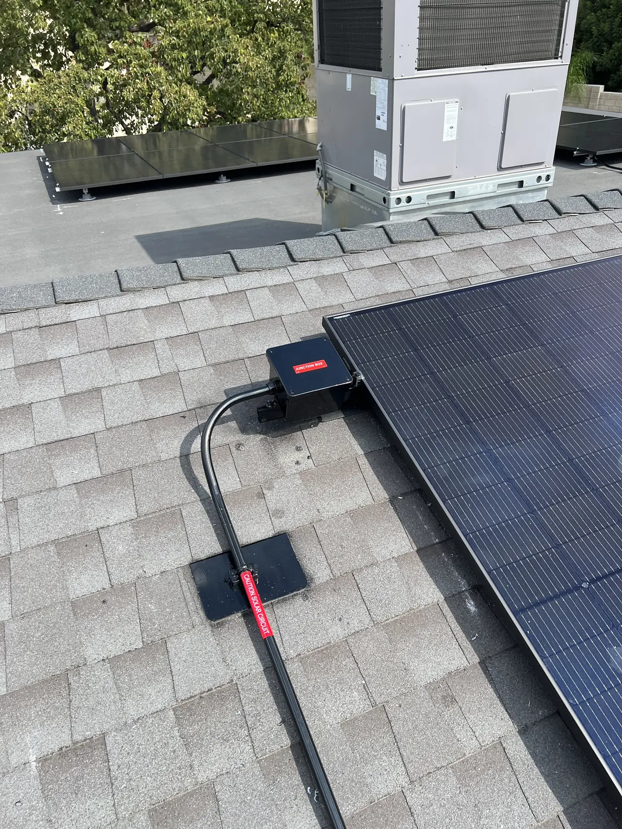 A solar module edge with its junction and cabling on a composition shingle roof, Granada Hills