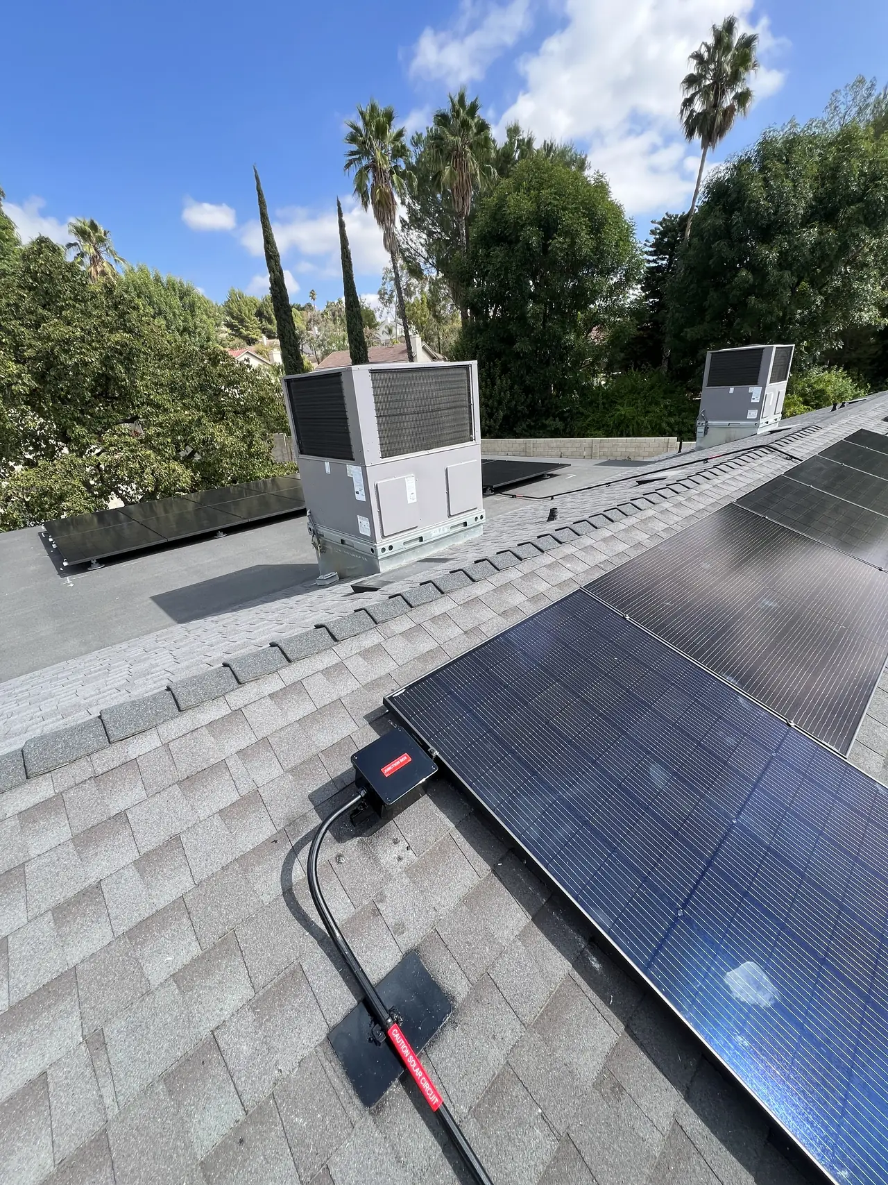 Solar modules across a shingle roof alongside rooftop air-conditioning units, Granada Hills