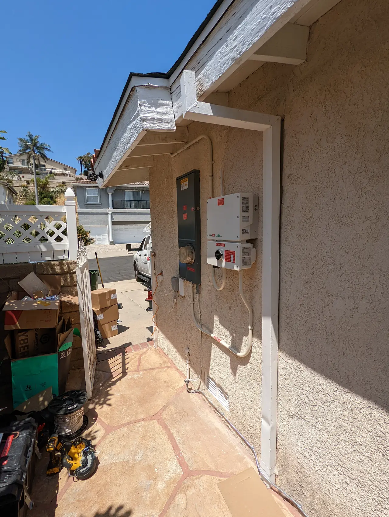 A service panel and inverter on the exterior wall of a house at the end of a paved side passage, Granada Hills
