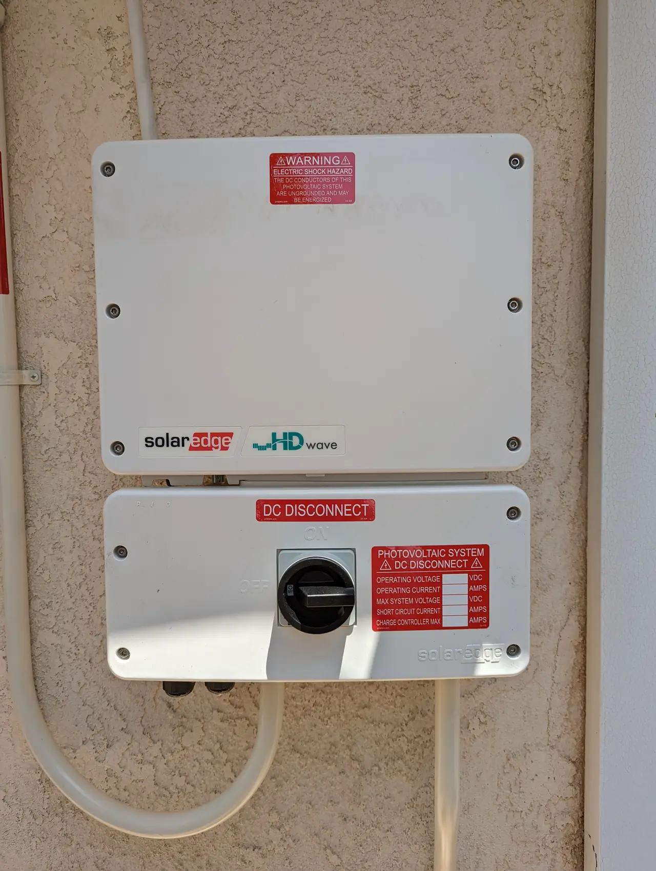A string inverter and its DC disconnect mounted on a stucco wall, Granada Hills