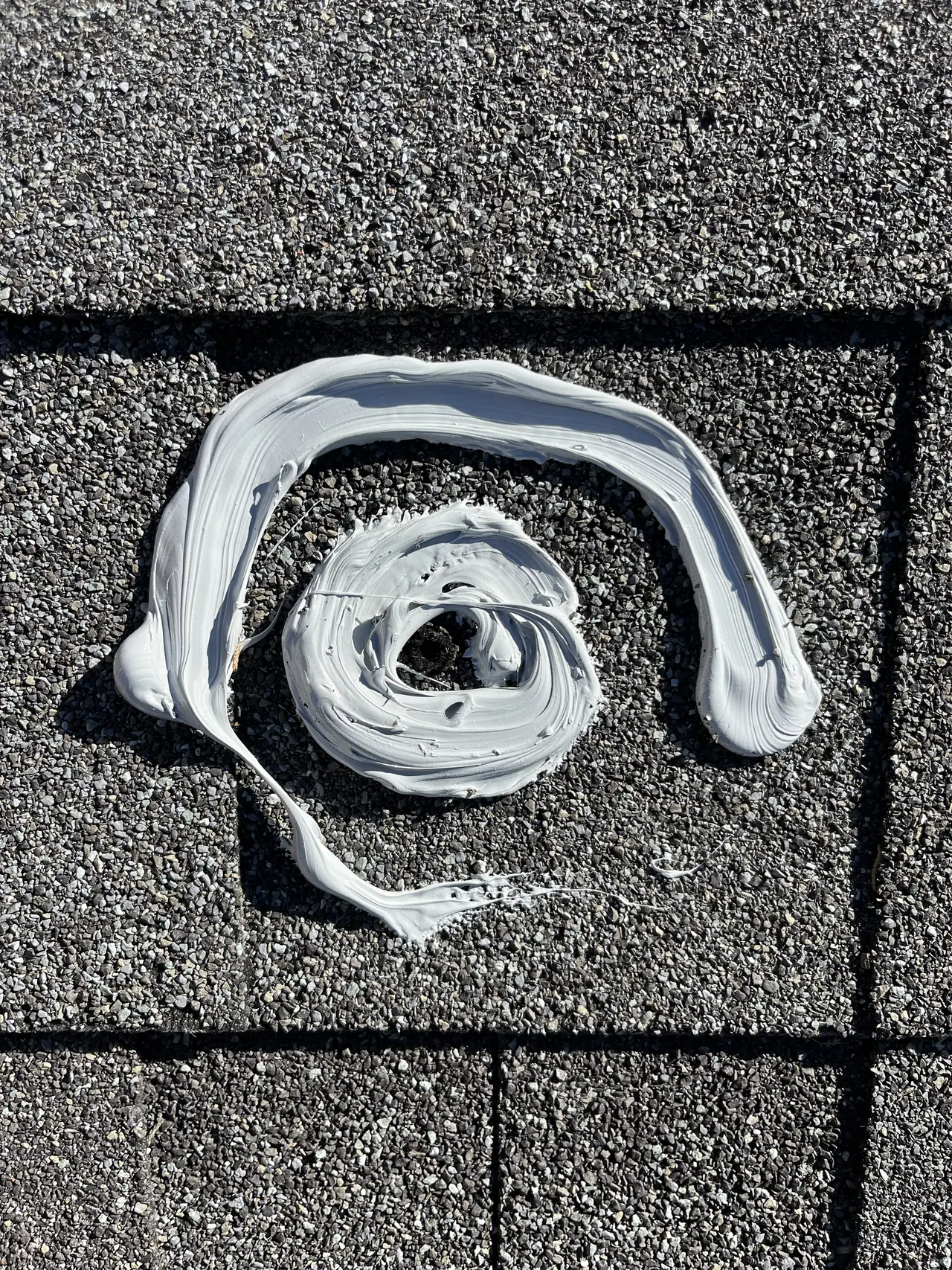 A horseshoe-shaped bead of sealant applied around a fastener hole on a composition shingle roof, open at the downhill side, Granada Hills