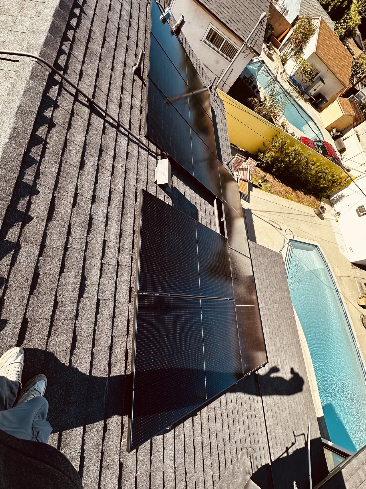 Solar modules on two separate planes of a hipped roof with a pool in the yard below, Granada Hills