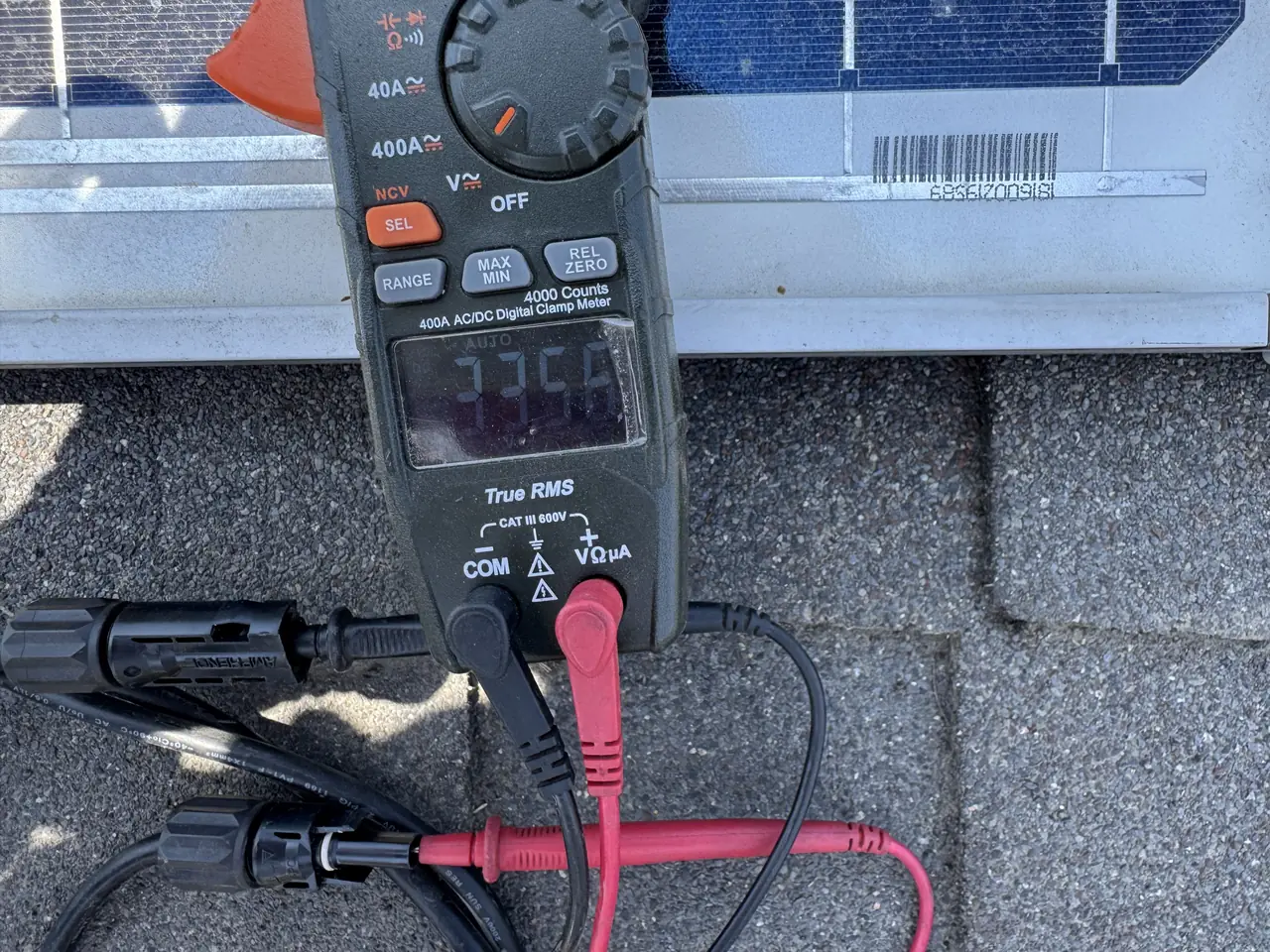 A clamp meter connected to a module connector on a roof, with the display reading, Granada Hills