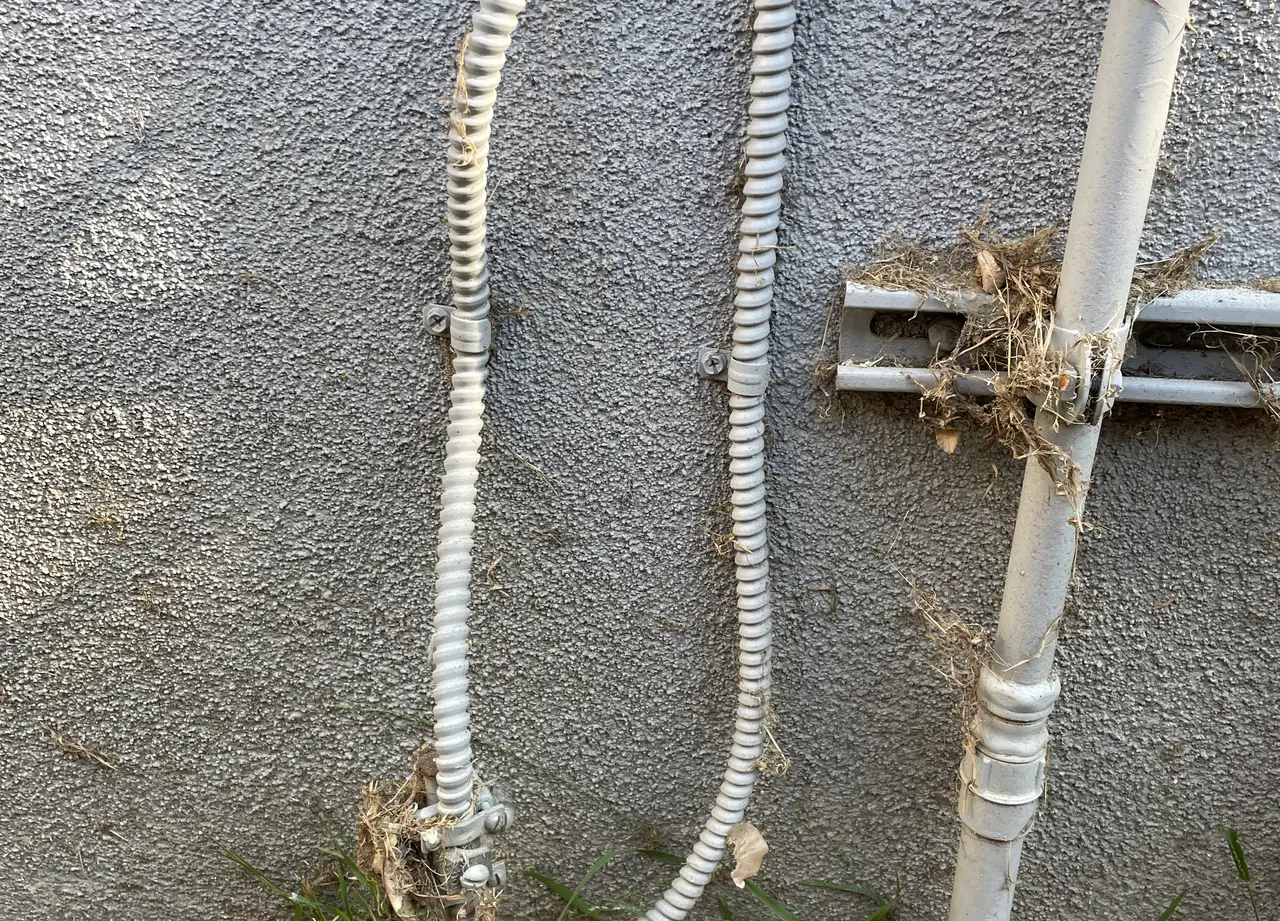 Grounding conductors in flexible conduit running down a stucco wall to the ground, Long Beach