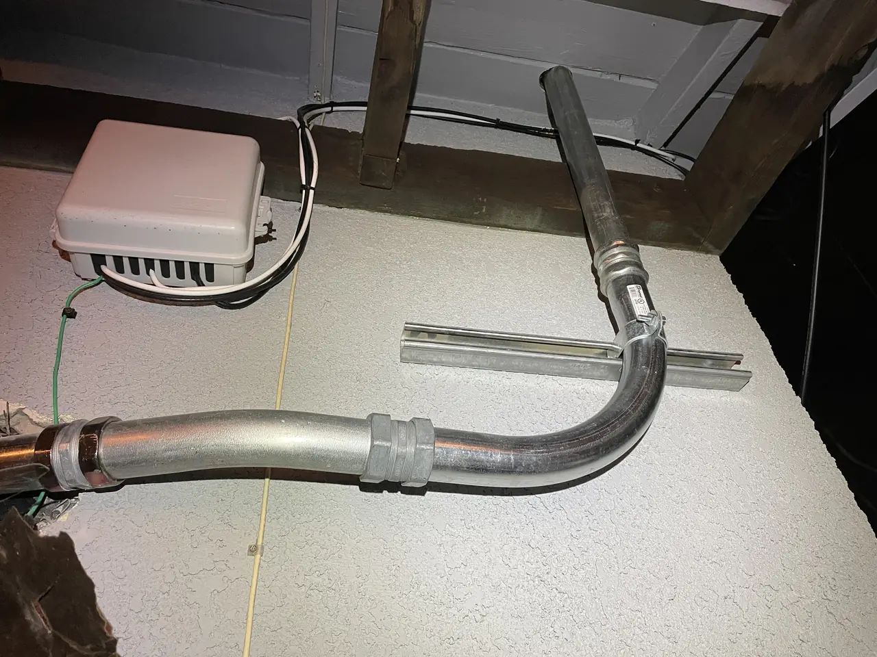 A galvanized conduit sweep and a junction box mounted under a roof overhang, Long Beach