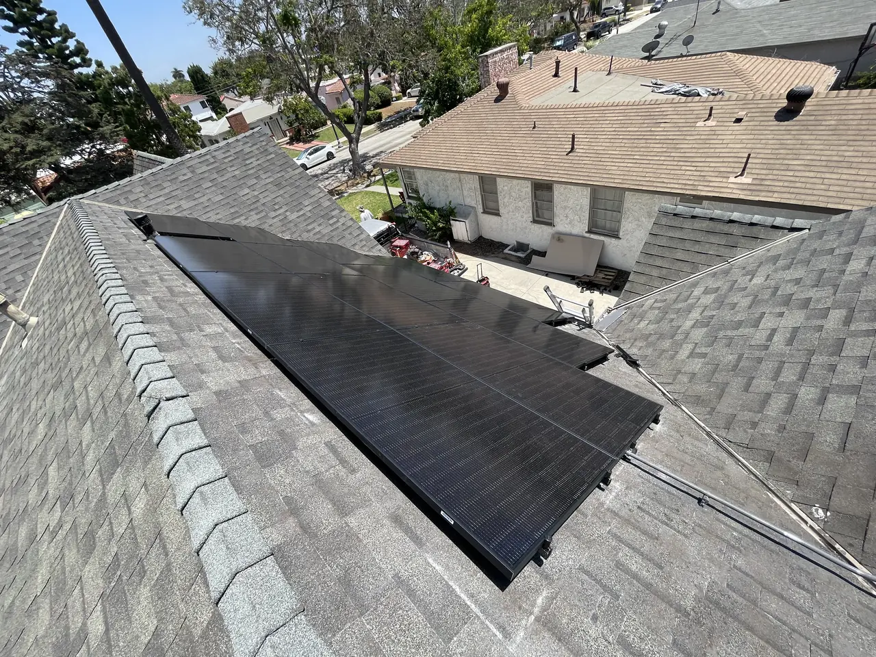 Groups of solar modules following the turning faces of a hip roof above a residential street, Long Beach