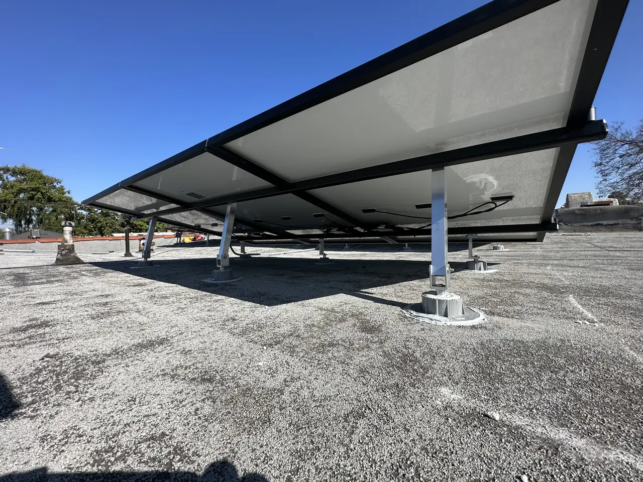The underside of a tilted solar array showing the legs and the gap above the flat roof, Long Beach