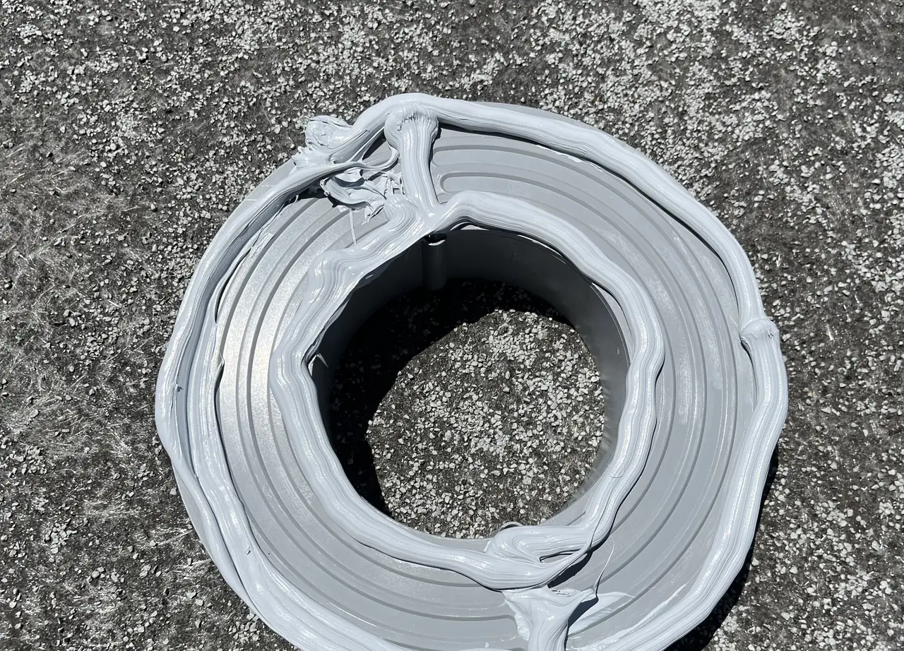 A standoff base sealed into a flat cap sheet roof with a thick collar of mastic, Long Beach