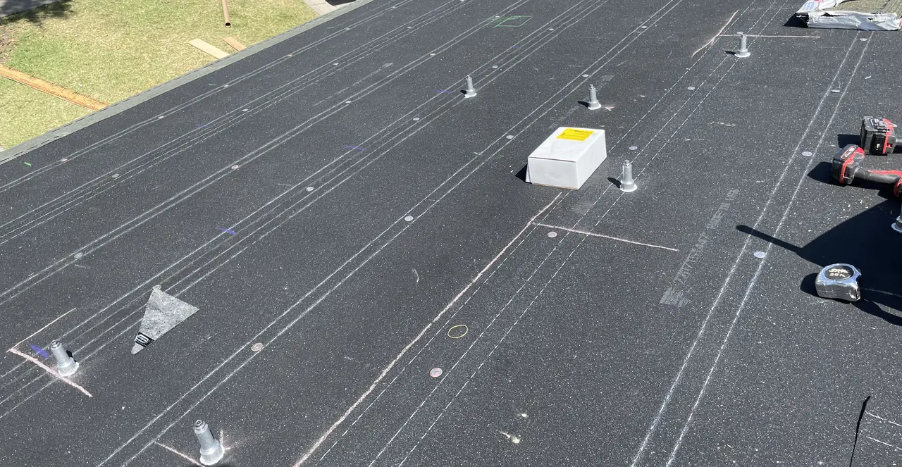A stripped roof deck with chalk lines running its length and mounting feet standing along them, Long Beach