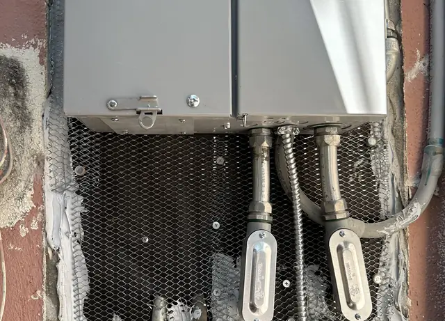New service equipment set into an opened stucco wall with expanded metal lath fitted around it ready for rendering, Long Beach