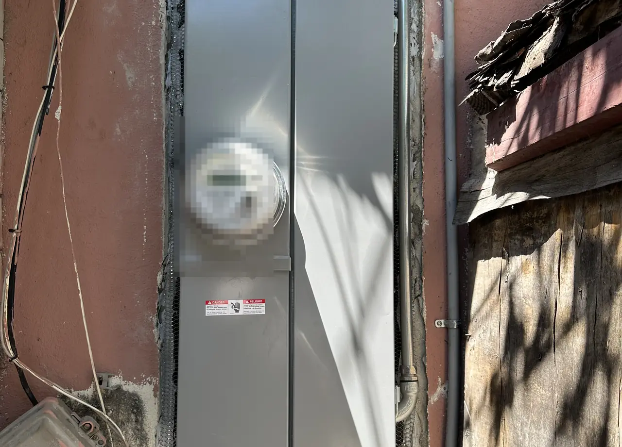 A meter enclosure set into an opened stucco wall with the wood lath exposed alongside it, Long Beach
